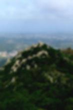 View of the Moorish Castle in Sintra, Portugal, on a hill surrounded by forest and light haze