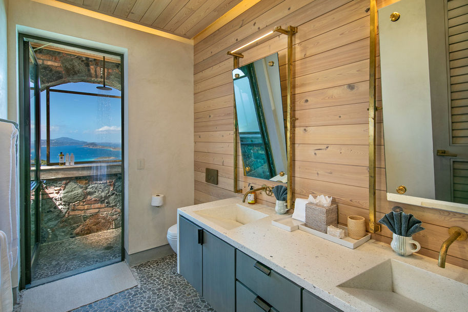 Bathroom with sinks, mirror, and exterior shower with a beautiful ocean view.