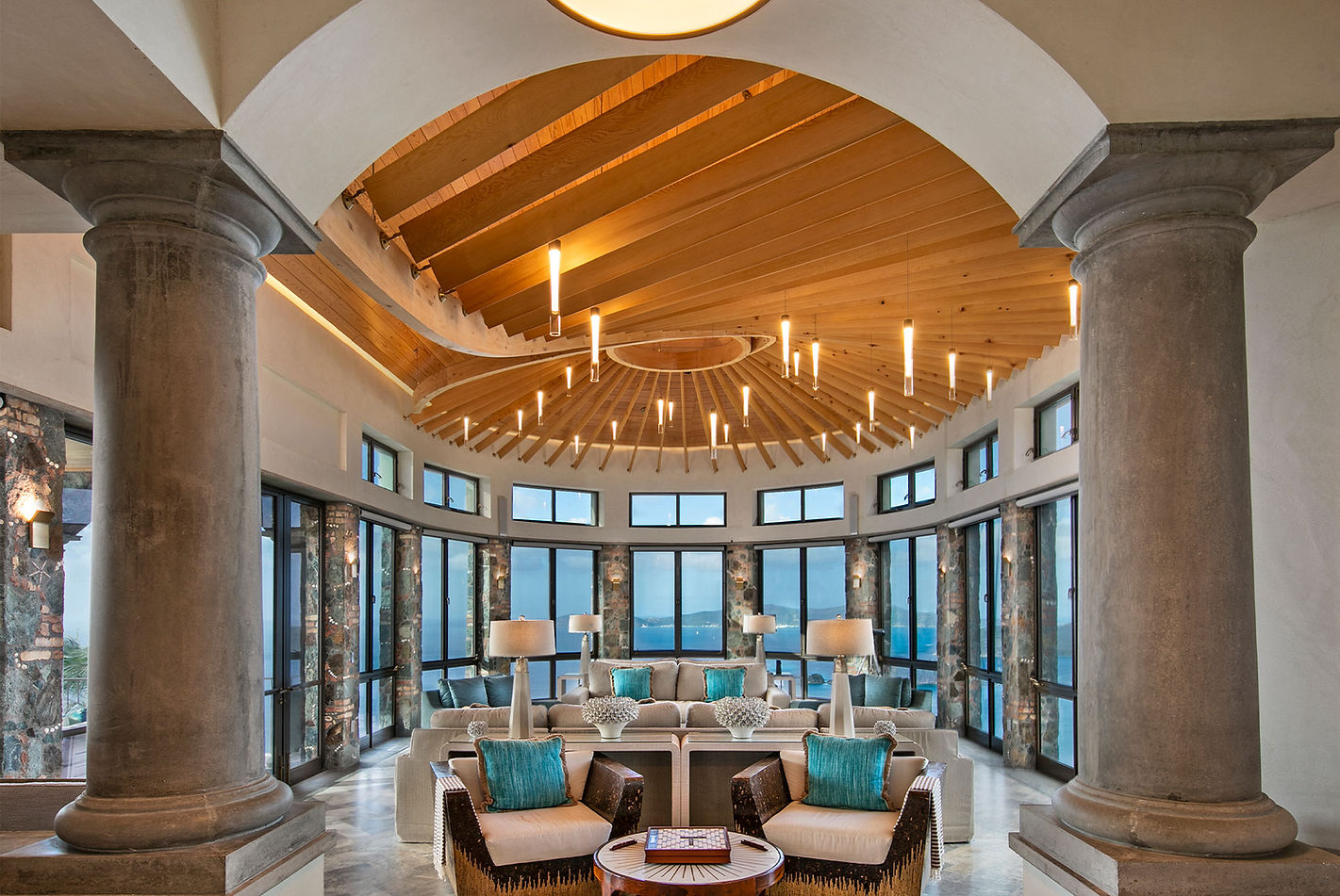 Luxury living room with large windows, columns, and a beautiful lounge area.