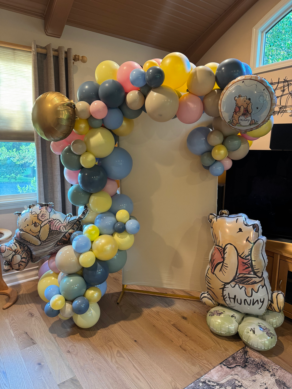 Pastel balloon arch with Winnie the Pooh party decorations
