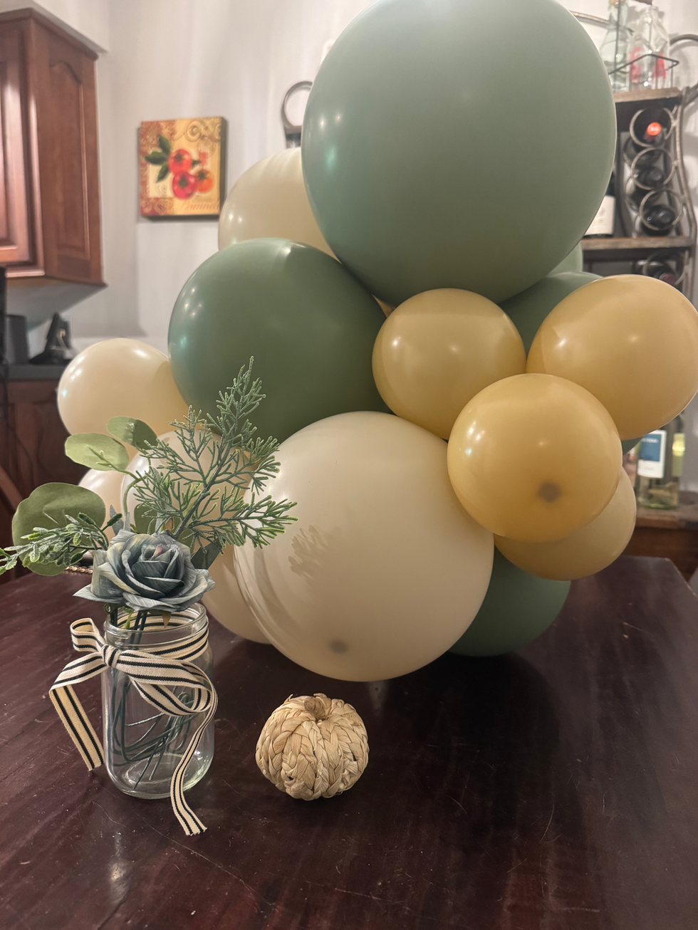 Holiday party decor: green & cream balloons, flowers, pumpkin