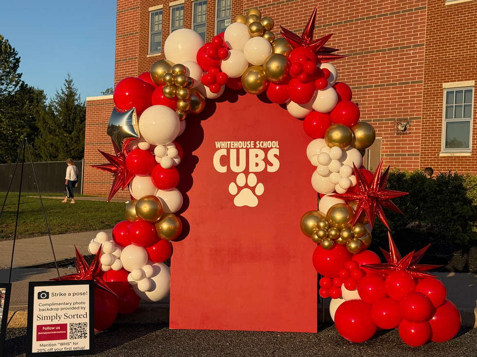 Red balloon arch with Whitehouse School Cubs sign