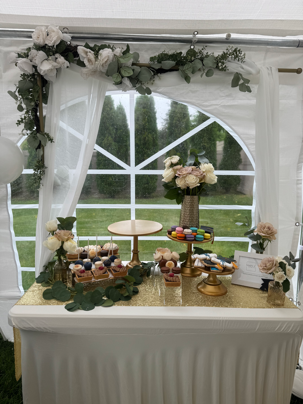 Elegant dessert table with cupcakes, macarons, and floral decor in tent