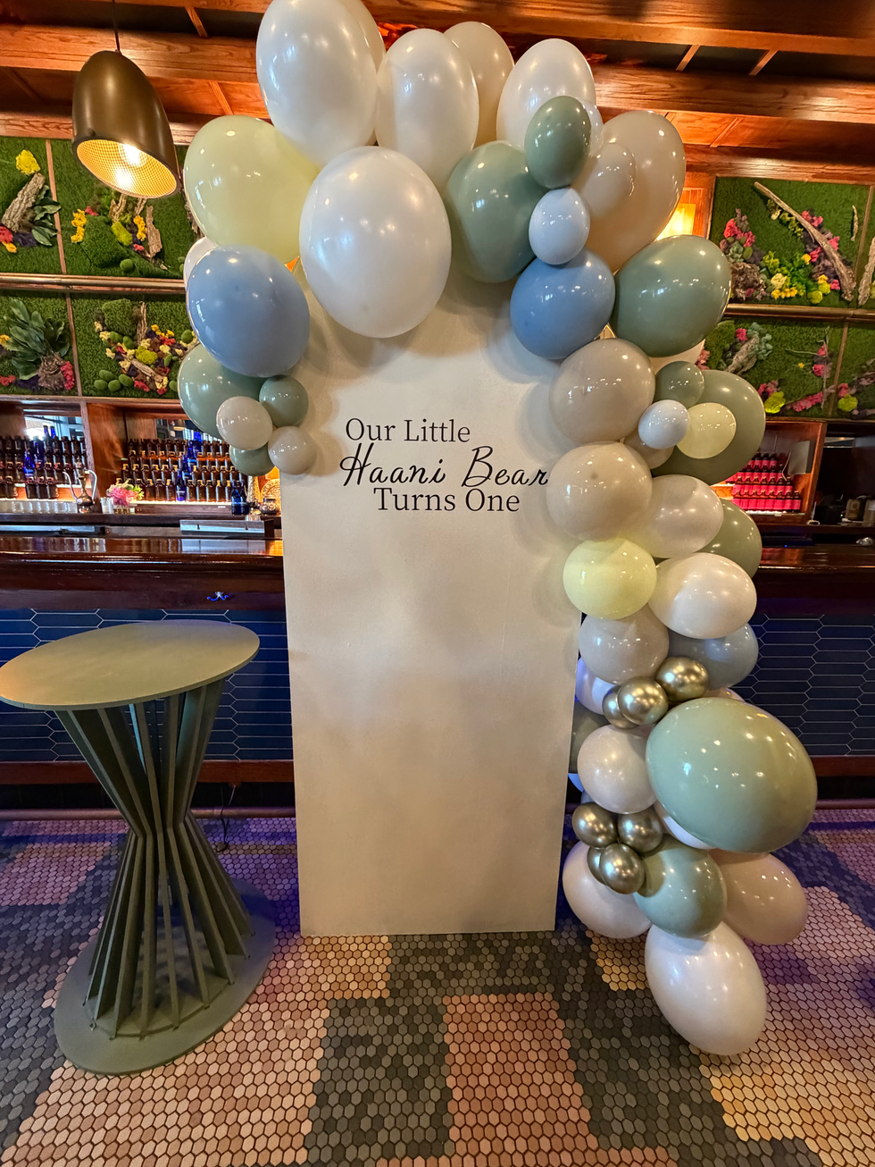 Muted balloons adorn 'Our Little Haari Bear Turns One' party sign