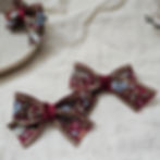 Thumbnail: Pair of maroon embroidered hair bows with gold trim and multicolour floral detailing.