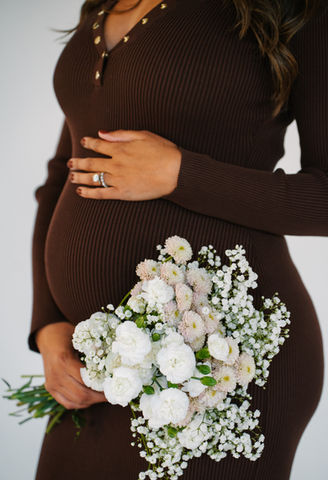 A sweet close up of a mom to be's belly adored with a bouquet of white flowers