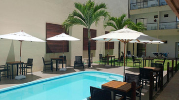 entretenimento piscina rodeada de mesas e guarda-sóis. POUSADA CANTO DOS CORAIS