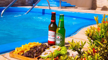 gastronomia uma bandeja de comida e cerveja ao lado de uma piscina. FLAT BADEJO