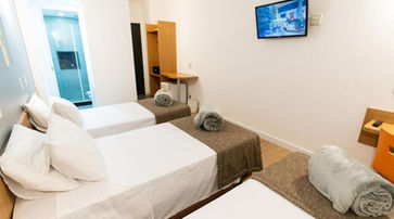 acomodacoes um quarto de hotel com três camas e uma tv de tela plana. HOTEL MEGA POLO 1