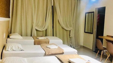 acomodacoes um quarto de hotel com três camas e uma escrivaninha. HOTEL GUARULHOS