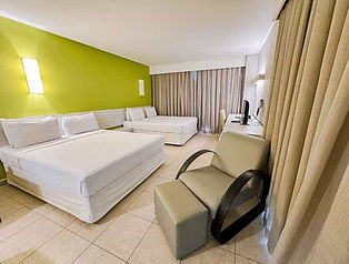 Quarto Master Plus com camas e poltrona e parede verde no Enotel Porto de Galinhas