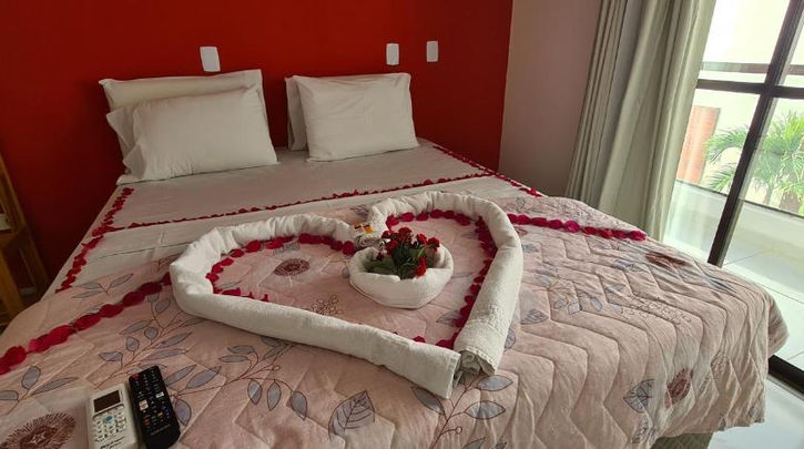 acomodacoes uma cama com uma bandeja de flores em cima. POUSADA CANTO DOS CORAIS