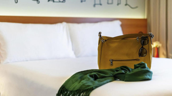 acomodacoes uma bolsa em cima de uma cama com um lenço verde. IBIS STYLES SP CENTRO 1