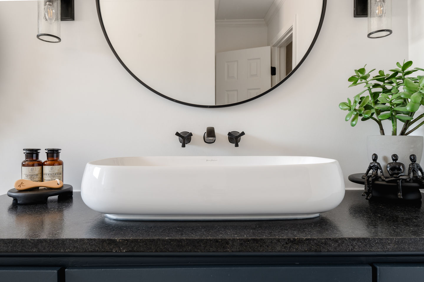 Modern vessel sink with wall-mounted faucet and dark countertop in Dallas bathroom renovation