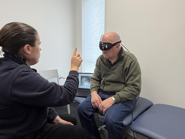 A client with vestibular assessment goggles in place being assessed by a Physiotherapist