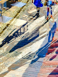 People walking down the street cast long shadows in the early morning light