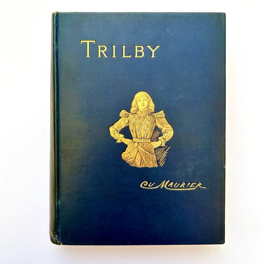Thumbnail: Front board close-up of Trilby with gilt illustration and lettering