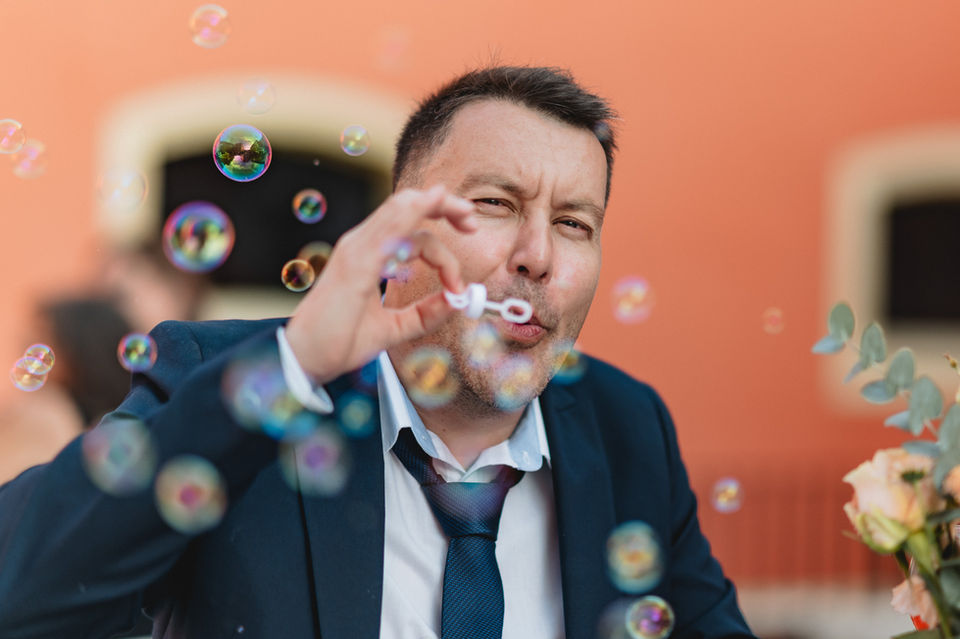 Wedding guest blowing soap bubbles during Kim and Dominique’s wedding reception in Luxembourg, candid moment photographed by wedding photographer Jérôme Neumann highlighting joyful celebration atmosphere.