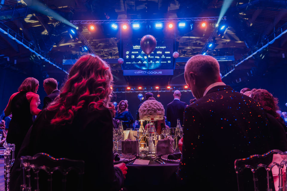 Guests seated at decorated tables under blue stage lighting during the Croix-Rouge Bal at Coque Luxembourg, photographed by corporate event photographer Jérôme Neumann.