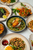 Various delicious local plates of food arranged on a white surface, ready to eat.