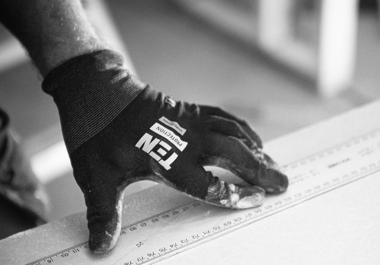 Working with a plaster wall cutting a board while using work gloves from Ten Protection._e