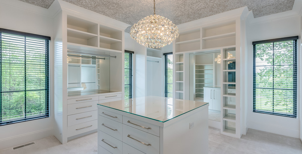 primary closet white chandelier and island storage