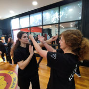 Δύο γυναίκες εξασκούνται σε ταυτόχρονη άμυνα και αντεπίθεση σε μάθημα γυναικείας αυτοάμυνας Wing Tzun.