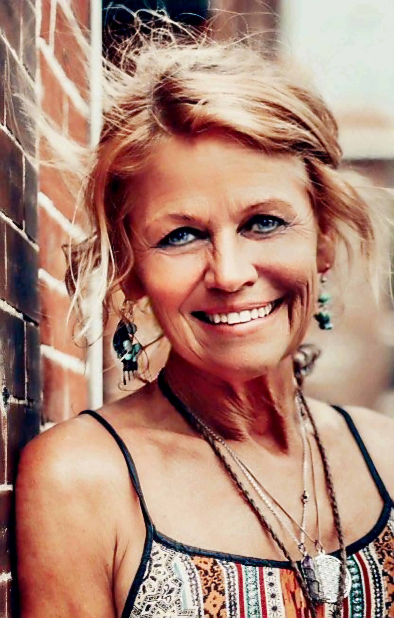 Jennifer Moen, founder of Carpe Diem Decor, smiling outdoors beside a brick wall