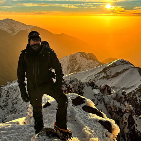 Climber on the summit of Mount Toubkal with the sunrising over the Atlas Mountains