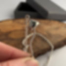 Sterling silver mushroom pendant held by the stem in the finger and thumb. It demonstrates the flexibility in the mushroom