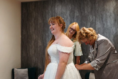 Bridesmaid and mother of bride helping with dress at East Mersea Hall wedding