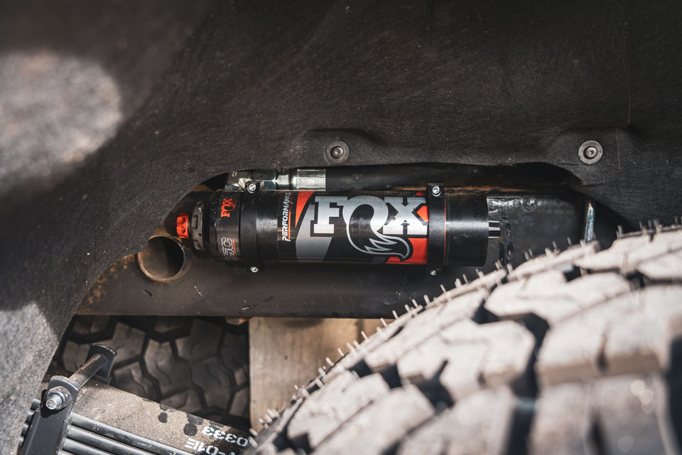 FOX remote reservoir shock mounted on Chevrolet Silverado 1500 ZR2 during Offroad Industries Stage 4 GVM upgrade installation, shown alongside all-terrain tyre.
