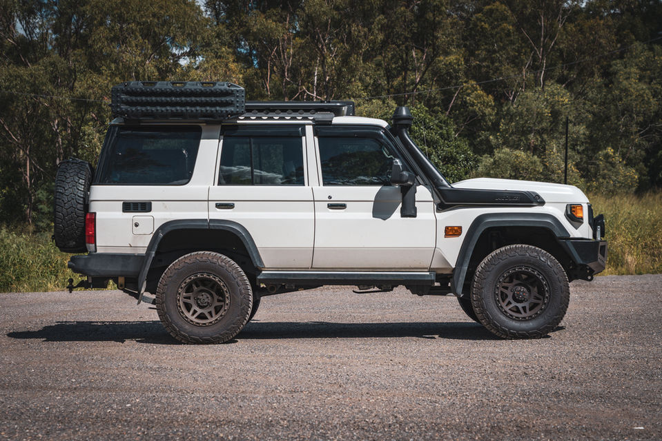 White 76 Series LandCruiser with roof platform and tradie-friendly setup in side profile.