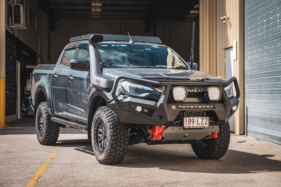 Grey Isuzu D-MAX with barwork, lift kit and off-road accessories outside workshop.