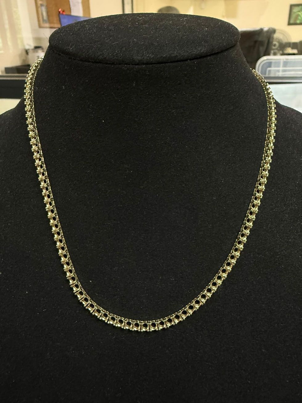 Solid gold diamond tennis necklace on a display bust
