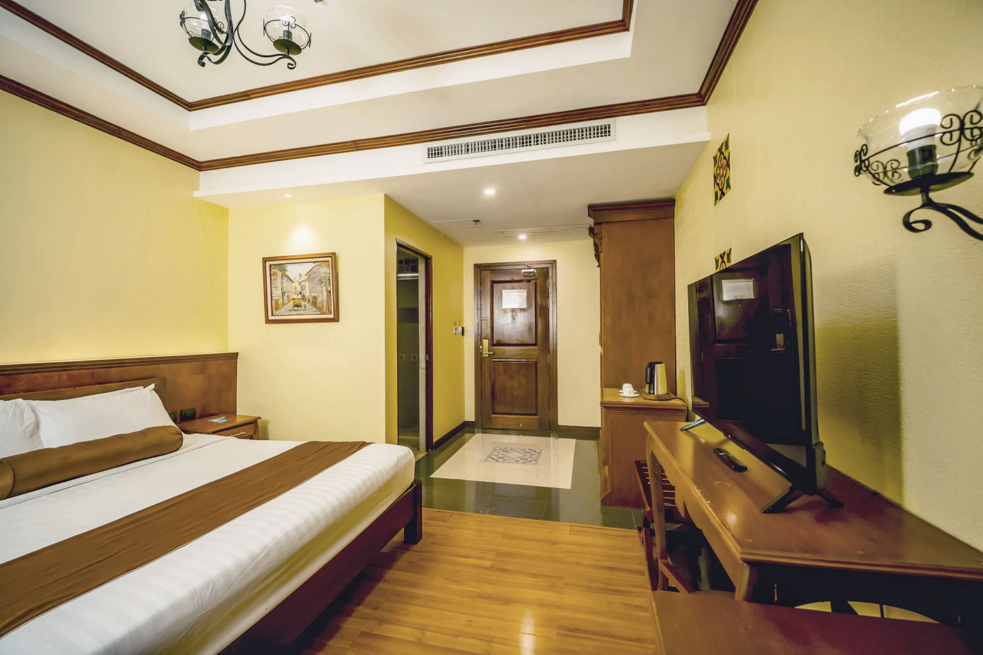 Queen sized bed against a wall with the Superior Room amenities around it