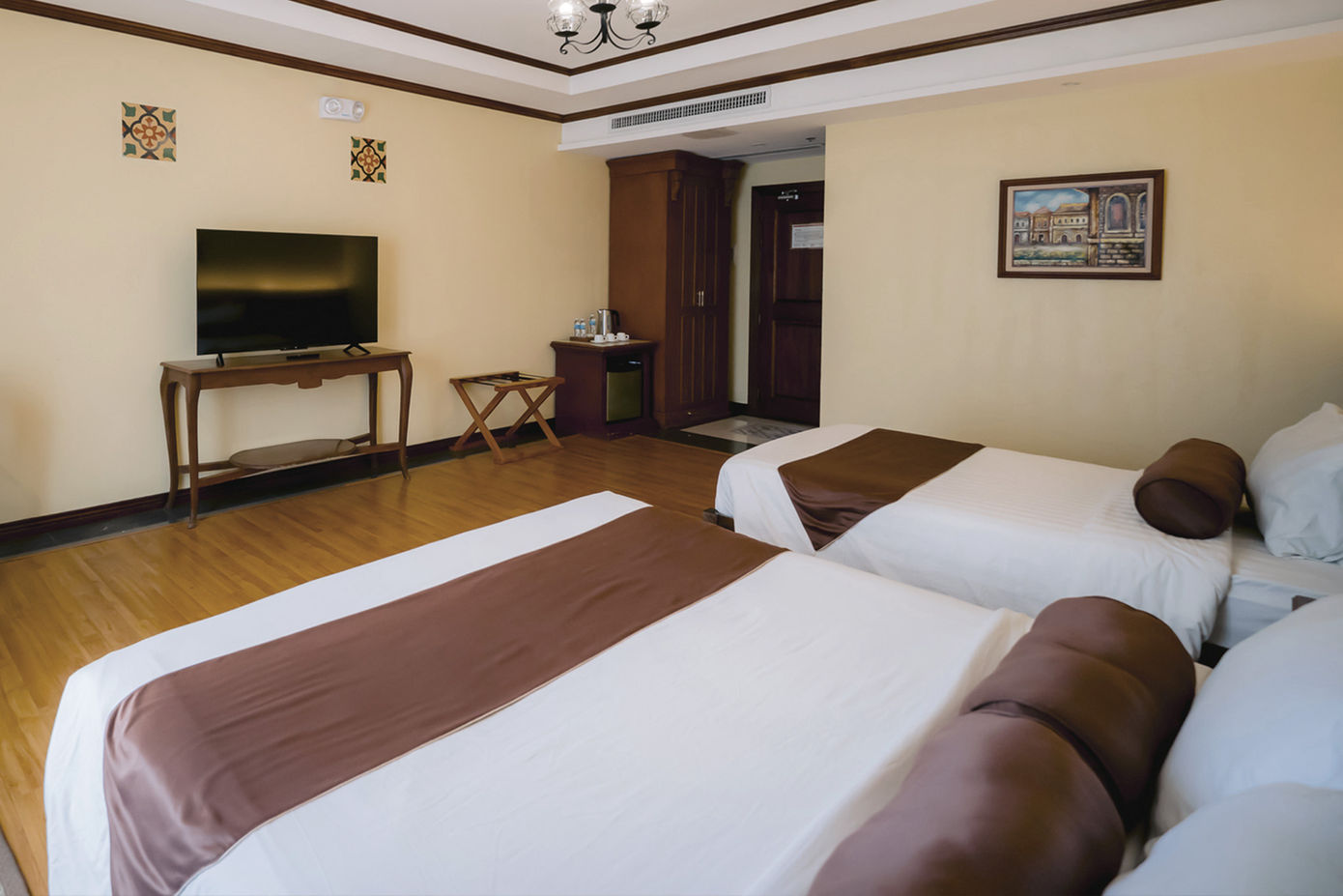 One king sized bed and one single bed against the wall with Deluxe Room amenities around them