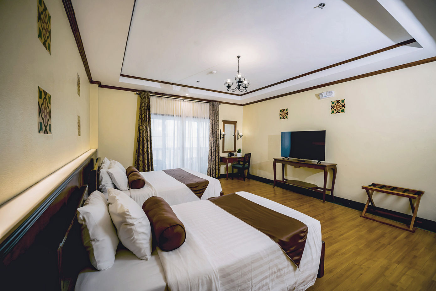 One king sized bed and one single bed against the wall with Deluxe Room amenities around them