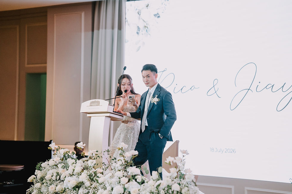 Rico and Jia Yi stand at the reception lectern beneath their projected names.