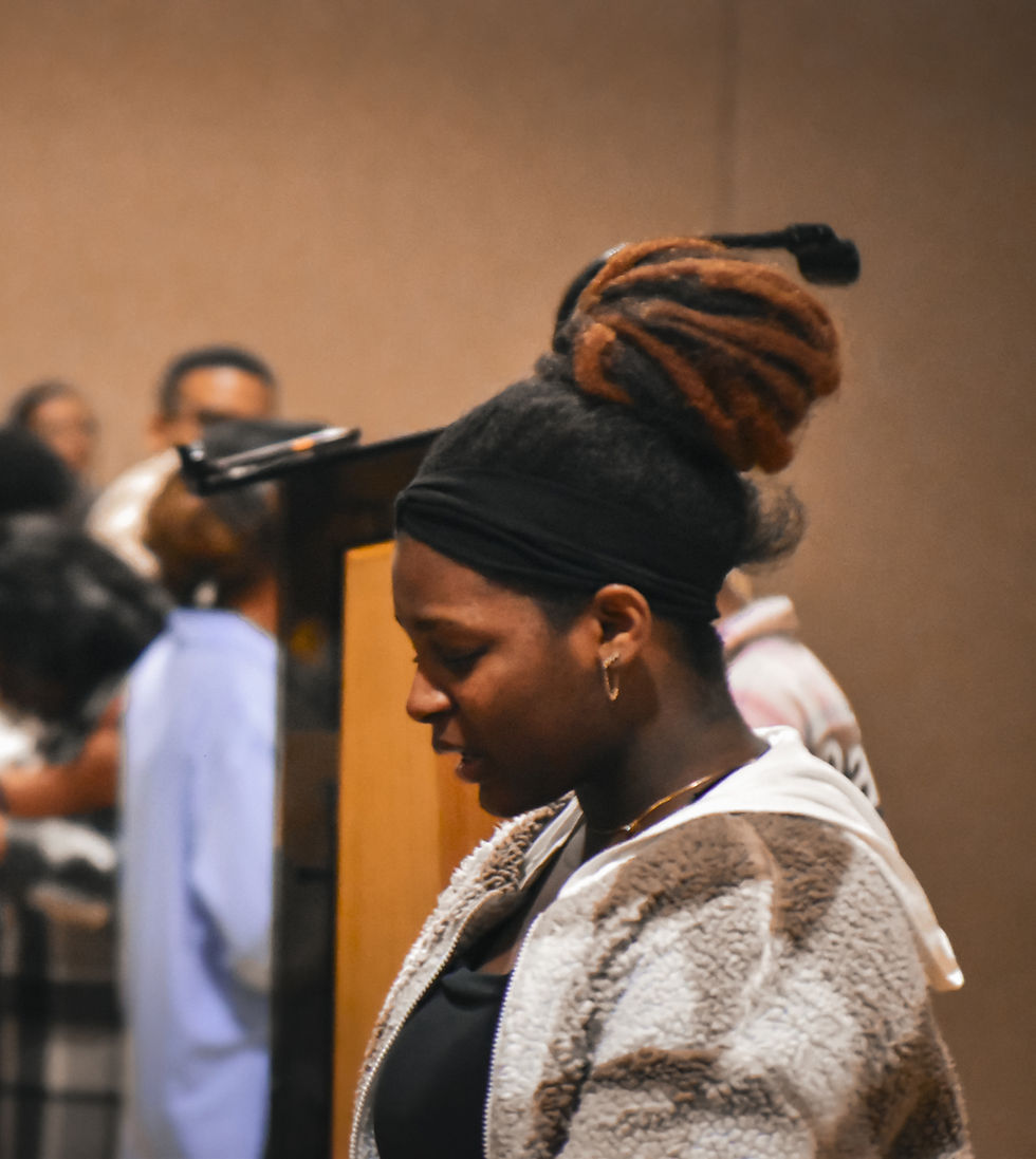 Young lady with a bun, head bowed, in prayer.