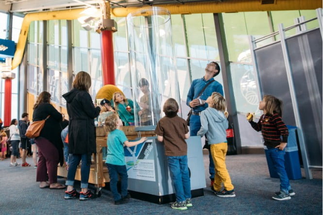 Children and families exploring a hands-on air vortex exhibit at a Florida indoor science center