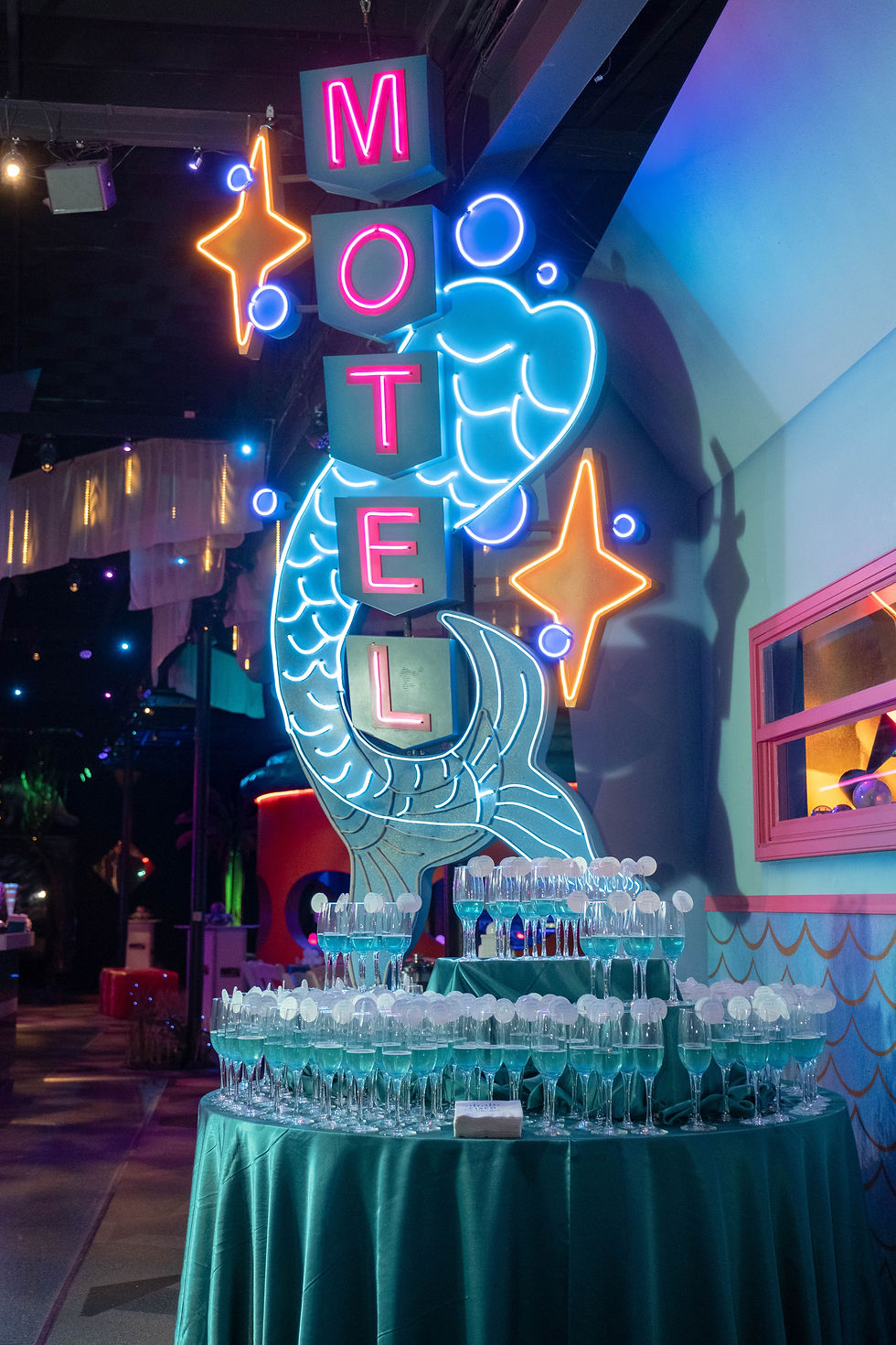 Neon mermaid motel sign glowing above a sparkling drink display at a unique bar mitzvah venue in Tampa Bay