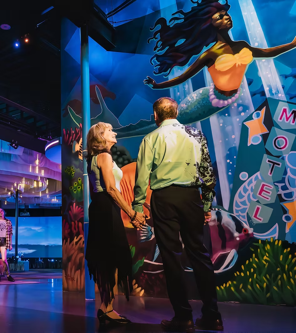 Couple holding hands while admiring the iconic mermaid mural at FloridaRAMA, one of St. Pete’s most unique date spots.