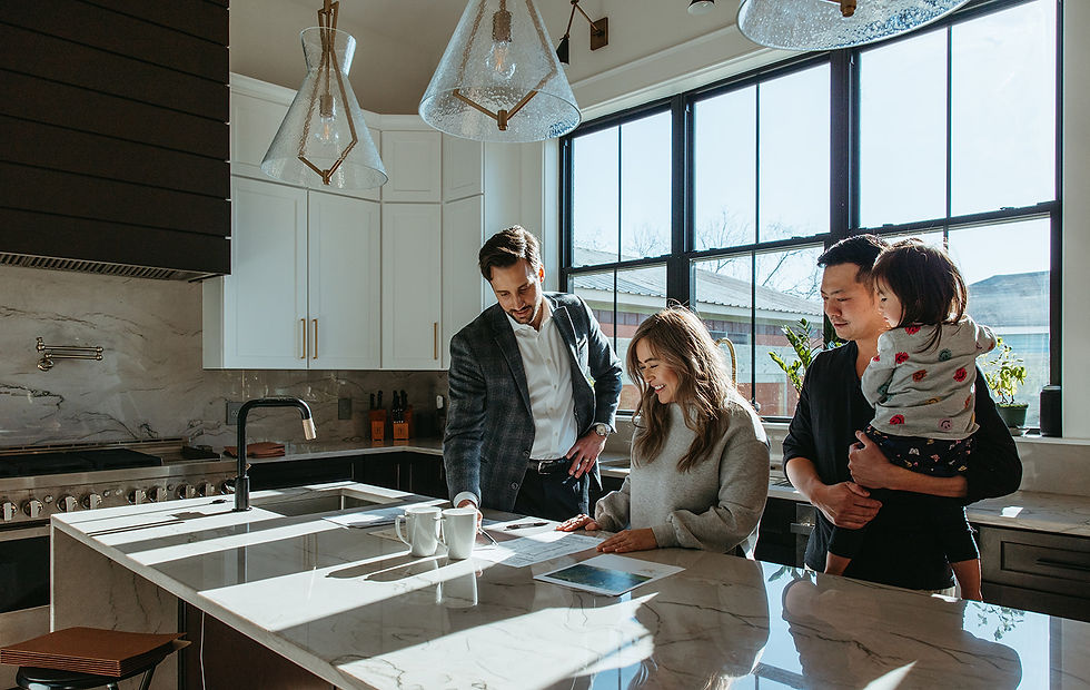 Three adults and a child in a bright kitchen review papers. Sunlight streams through the window onto the marble counter. Happy mood.