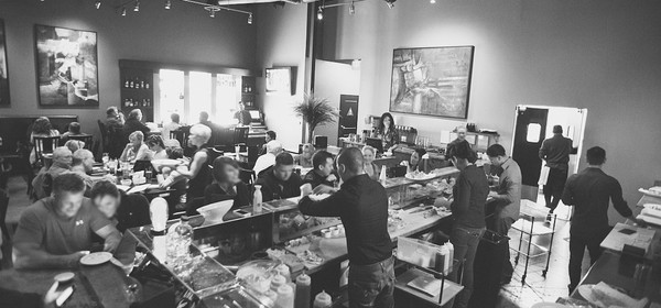 Warm, bustling interior of Raw Sushi Bistro with guests at the sushi bar