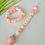 Thumbnail: Luxe handgemaakte bijtring in cream blush tinten met bloemdetail en naam ROSE.