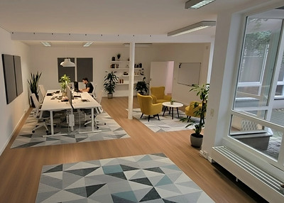 Heller Konferenzraum mit Tischen, Stühlen und Pflanzen; Coworking Berlin Mitte.