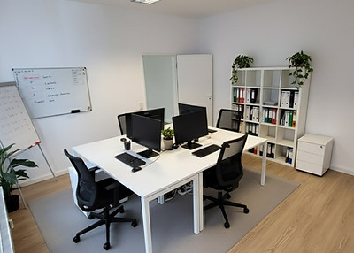 Helle, moderne Büroräume mit Computern, Tischen und Stühlen, leer, wartend.