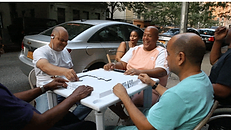Middle aged, bald hispanic men playing domino on a city side walk
