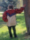 Back view of a man wearing a western mountain man shirt in colors of cream, oranges, and black